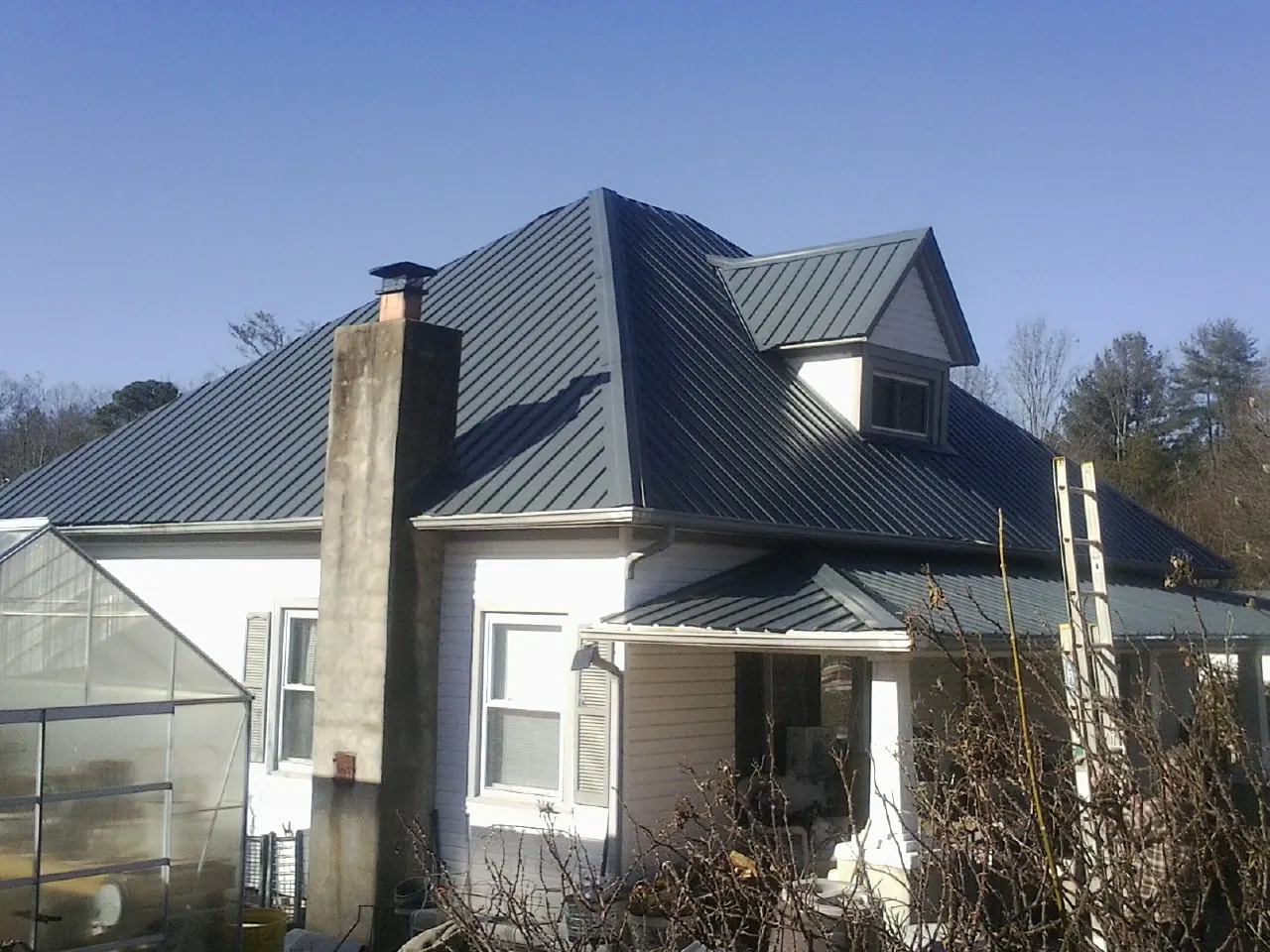 Dark blue standing seam metal roof on a white farmhouse with dormer — Slate & Tile Roof Repair by Roofing Brothers in Fogelsville