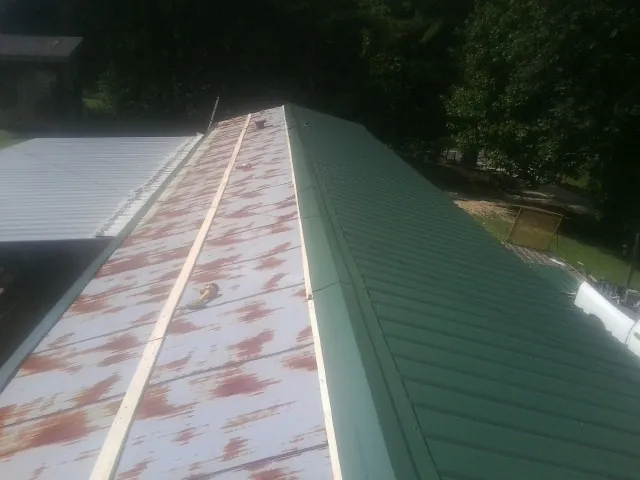Old rusted panels beside newly installed green metal roofing — Wind Damage Roof Repair by Roofing Brothers in Fogelsville