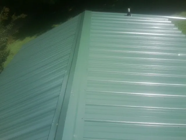 New green metal panels meeting at the ridge of a roof — Flat Roof Repair work by our crew in Fogelsville