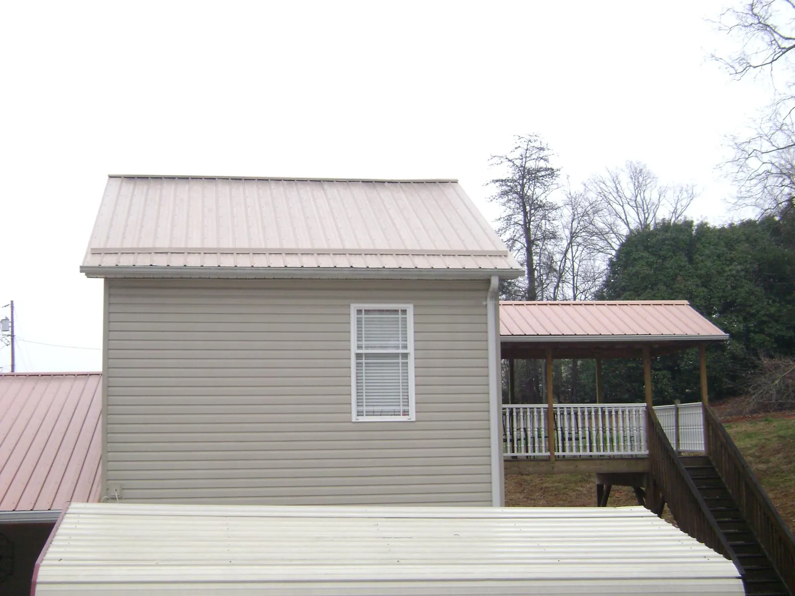 Tan metal roofs on a two story addition and attached porch, from a Roof Replacement job in Fogelsville