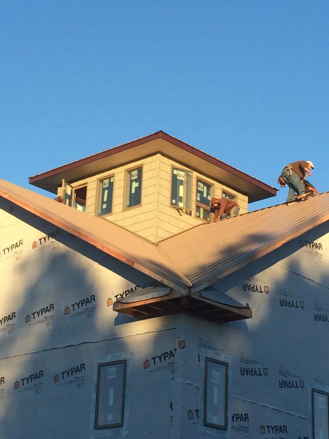Roofers working around a rooftop cupola on a new metal roof at sunset — Roof Waterproofing in Fogelsville by Roofing Brothers